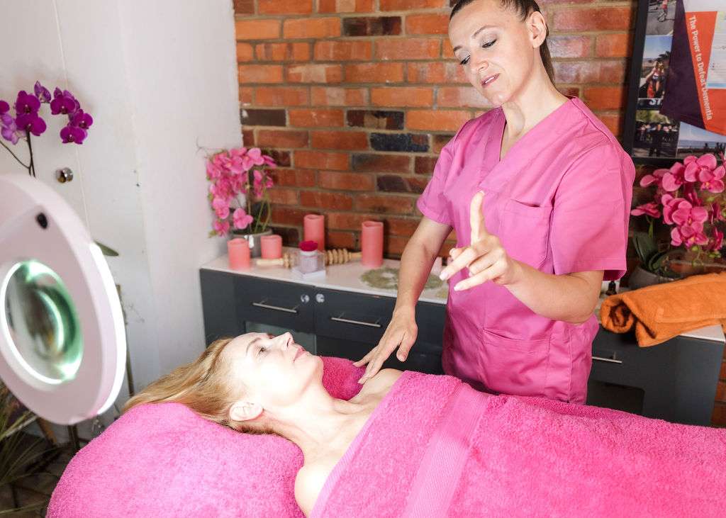 Alma demonstrating a facial massage technique using connective tissue massage tools to boost blood flow, increase circulation, release tension, and target areas like the inner corner of the eyes and double chin.